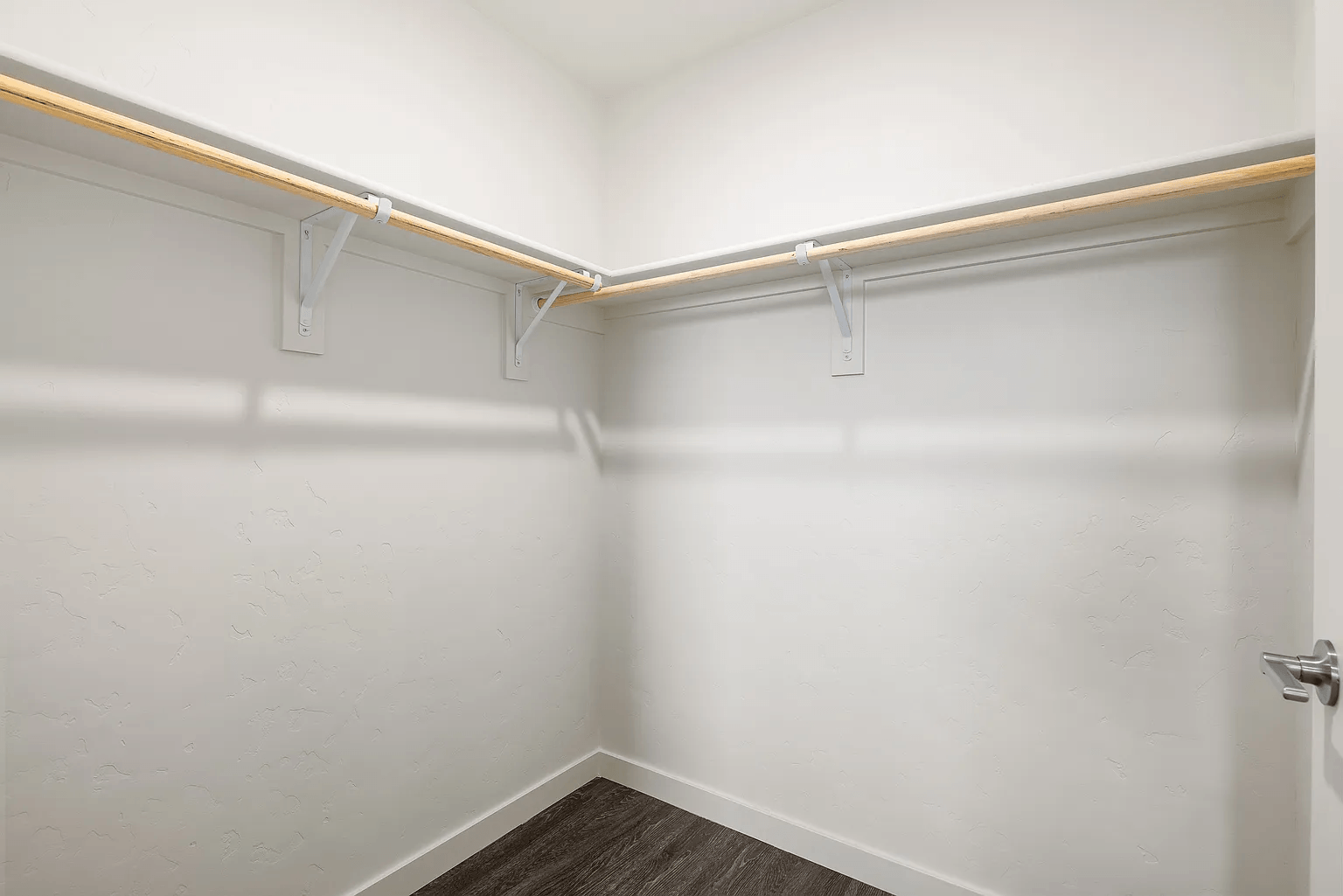 A white hallway with a brown floor and white walls.